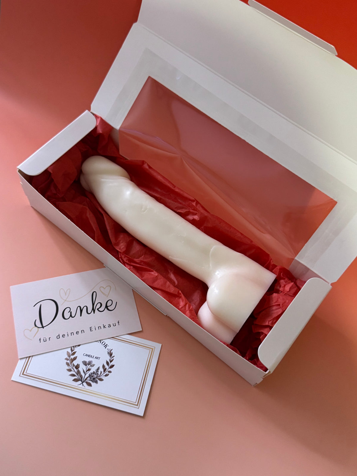 Weiße MARACUJA-Kerze in Penisform in einer weißen Geschenkbox mit rotem Seidenpapier.